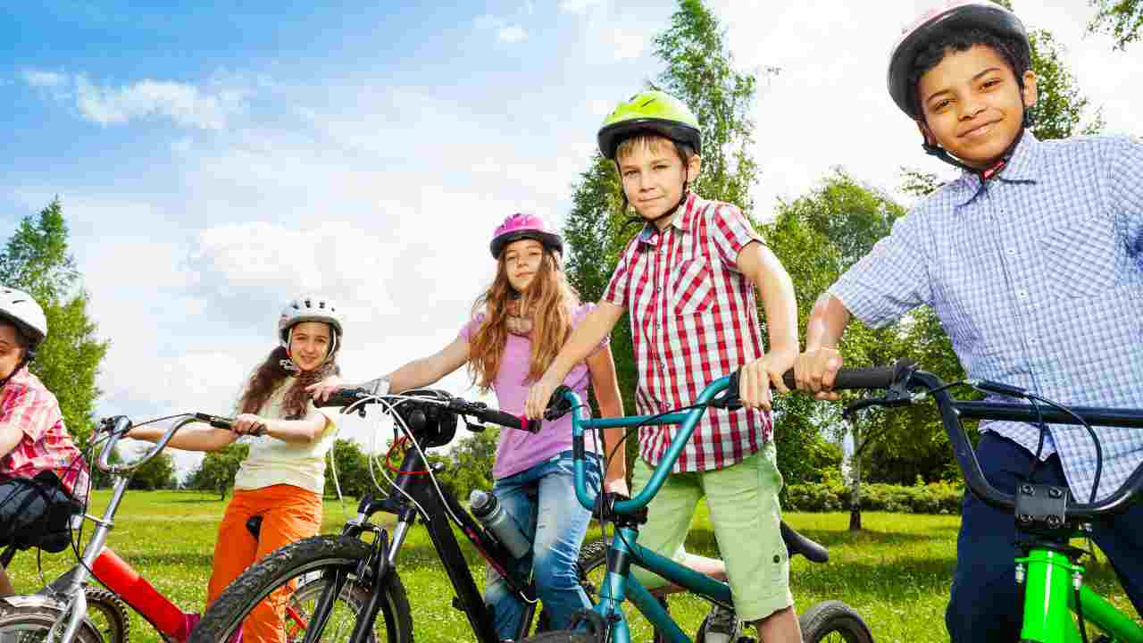 bambini con casco in bicicletta