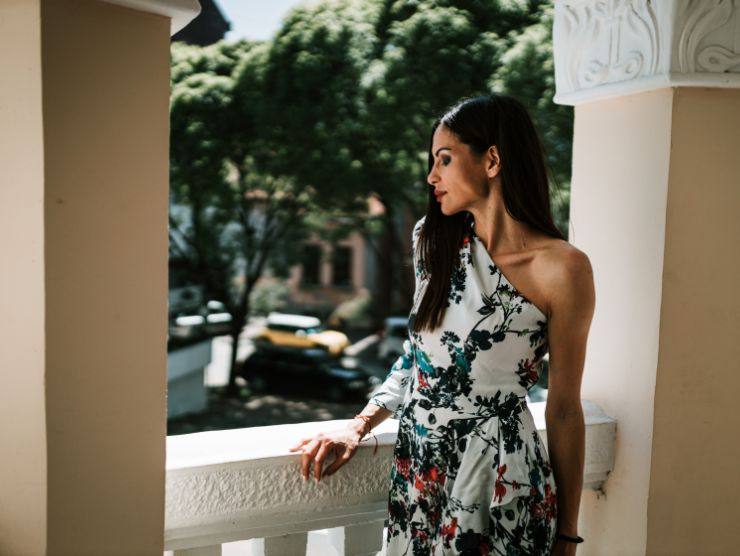 donna in posa affacciata ad un balcone con indosso un abito elegante