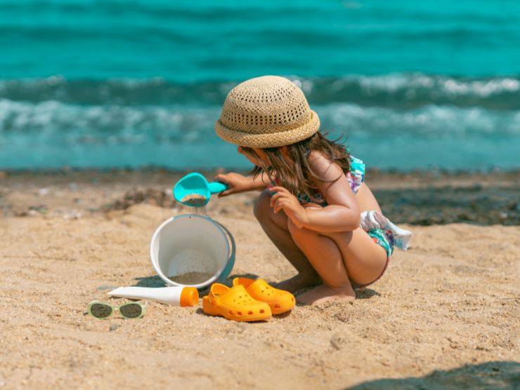 bimba che gioca in costume in riva al mare