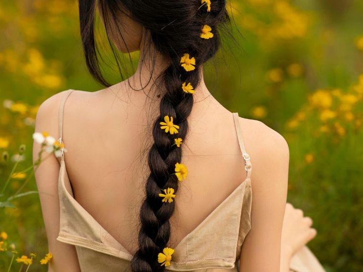 donna in un prato con capelli lunghi intrecciati